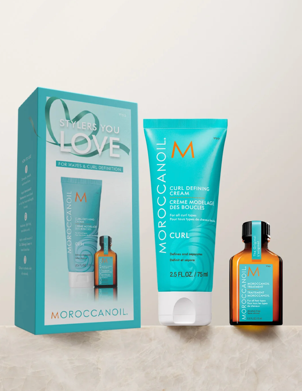 Moroccanoil curl defining cream gift set featuring a turquoise box, a matching tube of curl defining cream, and an amber bottle with a turquoise cap on a light beige background.