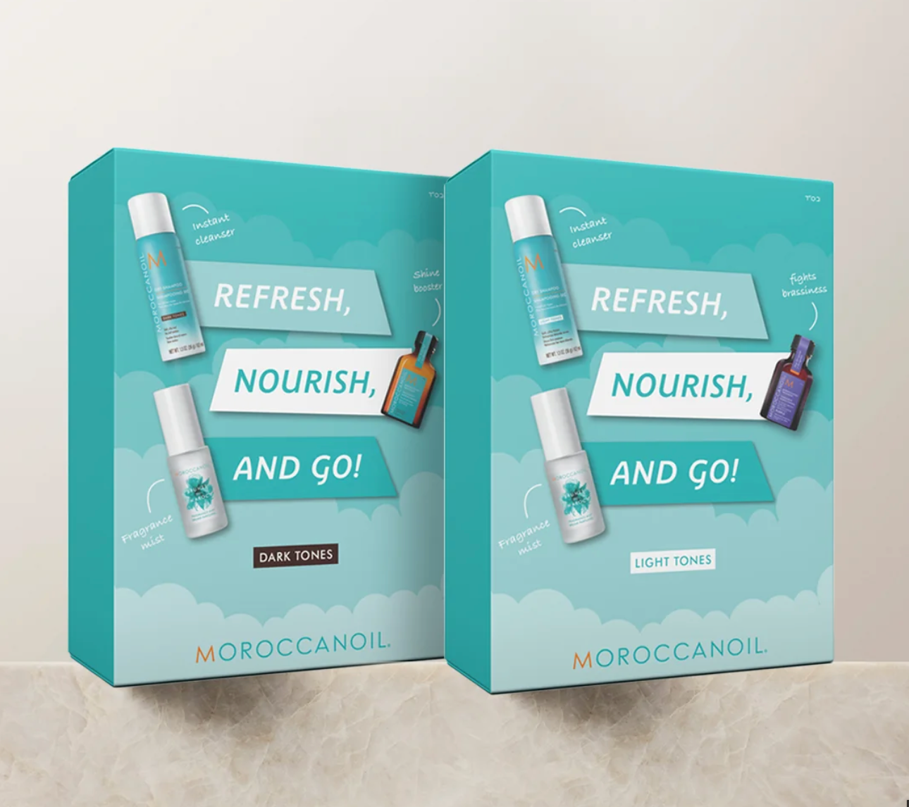 Two MOROCCANOIL product boxes standing upright on a light stone surface against a beige wall. The boxes are turquoise and white with cloud graphics and text reading 'REFRESH, NOURISH, AND GO!' plus shade names 'DARK TONES' and 'LIGHT TONES'.