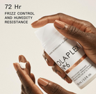 Olaplex hair treatment product held by a hand with text about frizz control and humidity resistance.